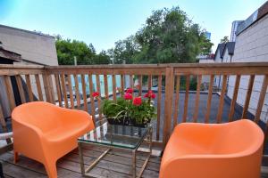 two orange chairs and a table with flowers on a balcony at Downtown Retreat-Spacious Rooms with Shared Kitchen & Bath in Toronto