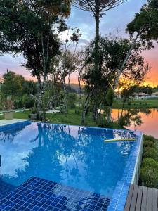 a swimming pool with a sunset in the background at Casa de campo com piscina em meio à natureza in Campo Magro