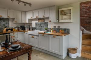 a kitchen with white cabinets and a wooden table at Moorland View Lodge in Baslow