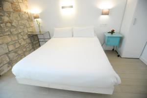 a white bed in a room with a stone wall at Artea Narrika in San Sebastián