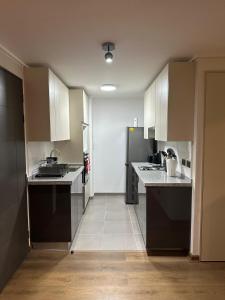 a kitchen with white cabinets and black appliances at Amplio departamento en zona céntrica de Concepción in Concepción +7 photos