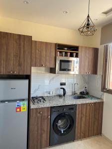 a kitchen with a washing machine and a microwave at Maison de paon - surfstay - relaxstay in Tamraght Ouzdar