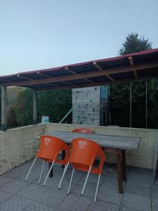 two orange chairs and a wooden table on a patio at O Canto do Melro, Guest House in Cortegaça