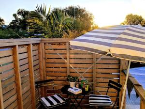 a patio with an umbrella and two chairs and a table at Tree House Jan Juc in Torquay