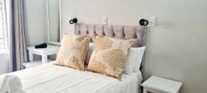 a bed with white sheets and pillows in a bedroom at Chakas Rock Beach Chalet 32 in Ballito