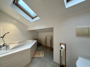 łazienka z wanną, umywalką i oknem dachowym w obiekcie Villa Forêt et Spa w mieście Champdray