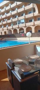 a swimming pool with chairs and a table in front of a building at Apartamento El Medano Marineda Loft in El Médano