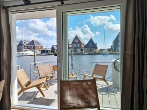 a balcony with chairs and a view of the water at Exclusive houseboat experience in Stavoren