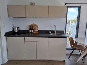 a kitchen with white cabinets and a sink and a table at Exclusive houseboat experience in Stavoren