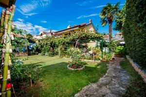 een tuin met een huis en een palmboom bij Apartments and Rooms Villa Dea in Rovinj