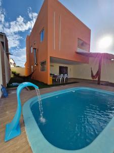 a pool with a water slide in front of a house at Casa do Pescador - Paripueira in Paripueira