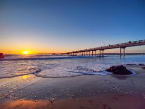 a pier on the beach at sunset with the ocean at Modern Newly Renovated 2BR Apt in Heart of Ocean Beach in San Diego