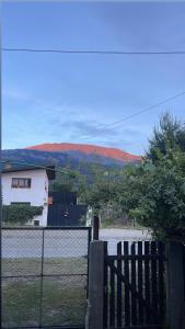una cerca frente a una casa con montañas en el fondo en Entre Jardines, en El Bolsón 26 fotos más
