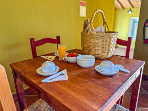 a wooden table with dishes and a basket on it at Casas do Palheiro Velho in Castro Marim