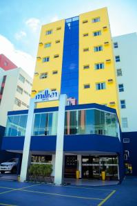 a yellow and blue building with a car parked outside at Millian Hotel in Jundiaí