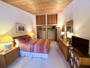 Un dormitorio con una cama y un televisor de pantalla plana. en Hidden Village 724, en Big Sky