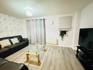 a living room with a black couch and a glass table at Sabino View - 4 Bed Yorkshire Nest in Cudworth