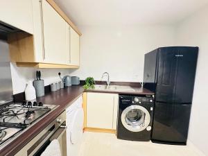 a kitchen with a black refrigerator and a washing machine at Sabino View - 4 Bed Yorkshire Nest in Cudworth