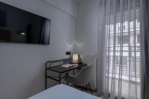 a bedroom with a desk and a bed and a window at Embassy Elegant Suite in Thessaloniki