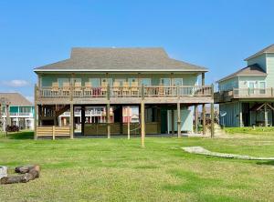 a large house with a deck on a lawn at Fire and Ike - A stunning 4 bedroom, 3 bathroom, Beachfront Retreat! Massive Lot Packed w Amenities in Crystal Beach