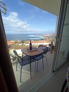 a table and chairs on a balcony with a bottle of wine at Apartamento Cactus in Bajamar