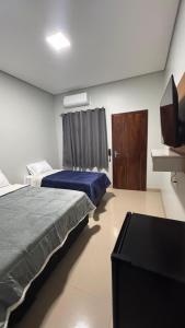 a bedroom with two beds and a television in it at Hotel Pousada Prime in Campo Novo do Parecis
