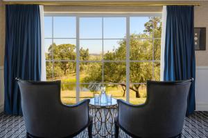 a room with a table and two chairs and a large window at voco® Kirkton Park Hunter Valley by IHG in Pokolbin