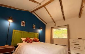 una camera da letto con un letto e una parete blu di Anido Hotel a Ollantaytambo