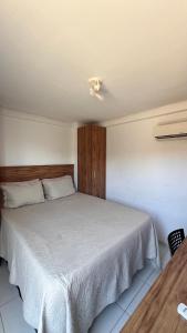 a bedroom with a white bed with a wooden headboard at Studio completo na praia de Manaíra, apt 213 in João Pessoa +8 photos