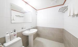 a white bathroom with a sink and a toilet at Jeju Orastay Hotel in Jeju