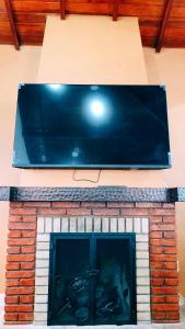 a large tv on top of a brick fireplace at Cantinho Dona Cleide in Monte Verde
