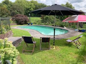 two chairs and an umbrella next to a swimming pool at Woodhey Retreat in Cambridge