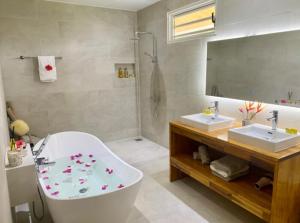 ein Badezimmer mit Badewanne, zwei Waschbecken und einem Spiegel in der Unterkunft Holiday house Nuupure - Accès plage privée & terrain de Pickelball in Maatea + 28 Fotos