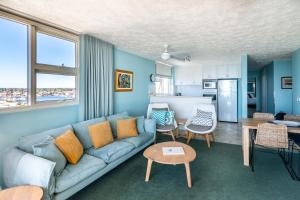 ムールーラバにある84 The Spit Holiday Apartmentsの青いソファとキッチンのあるリビングルーム