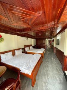 two beds in a room with a wooden ceiling at Nam Sông Hậu Hotel in Can Tho +9 photos