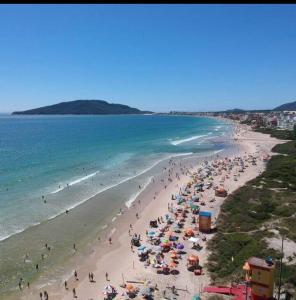 uma multidão de pessoas em uma praia com guarda-sóis em hostel praia dos ingleses em Florianópolis