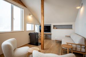 a living room with chairs and a refrigerator at Tanuki Nozawa in Nozawa Onsen