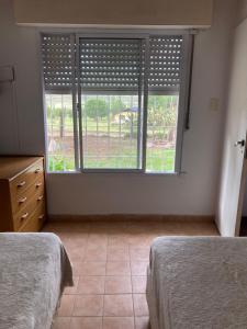 Un dormitorio con dos camas y una gran ventana. en Casa Las Dunas- 6 cuadras del mar, en Monte Hermoso