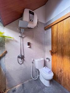 a bathroom with a toilet and a air conditioner on the wall at Briza La Barka Resort by Raminten in Moyudan