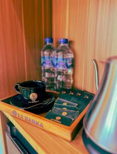 a table with a coffee cup and two bottles of water at Briza La Barka Resort by Raminten in Moyudan