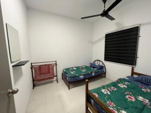 a room with two beds and a ceiling fan at EL Homestay in Melaka