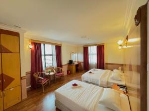 a hotel room with two beds and a desk at Flora Place Hotel in Kota Bharu +25 photos