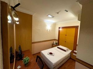 a hotel room with a bed and a table with a desk at Flora Place Hotel in Kota Bharu