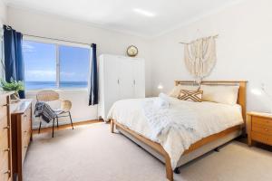 a bedroom with a bed and a large window at Glory House at Culburra - Beachfront in Culburra Beach
