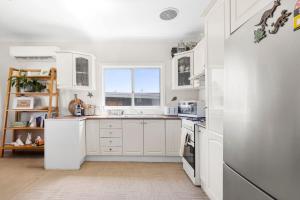 a white kitchen with white cabinets and a window at Glory House at Culburra - Beachfront in Culburra Beach
