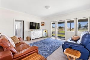 a living room with a couch and a tv at Glory House at Culburra - Beachfront in Culburra Beach