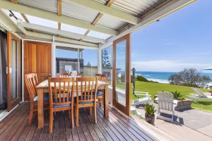 a dining room with a table and chairs on a deck at Glory House at Culburra - Beachfront in Culburra Beach