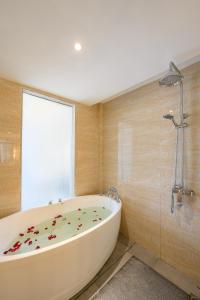 una bañera en un baño con ventana en โรงแรม จอมเทียน ฮอลิเดย์ พัทยา, en Jomtien Beach
