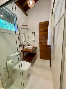 a bathroom with a toilet and a glass shower at CASA PREGUIÇA - TRANCOSO - ECO in Trancoso