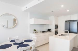 a kitchen with white cabinets and a table and chairs at MEGA VIEWS at Oracle - level 32 in Gold Coast